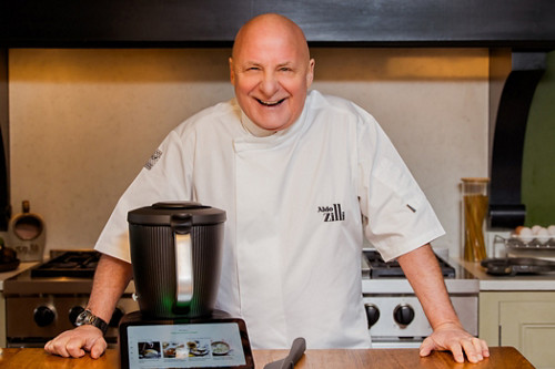 Aldo Zilli standing in the kitchen, smiling at the camera, Thermomix 7 in front of him