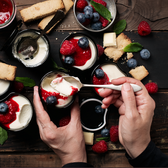 Vasetti di dessert con salsa di frutti rossi mirtilli lamponi menta cioccolato bianco e biscotti mani con cucchiaio