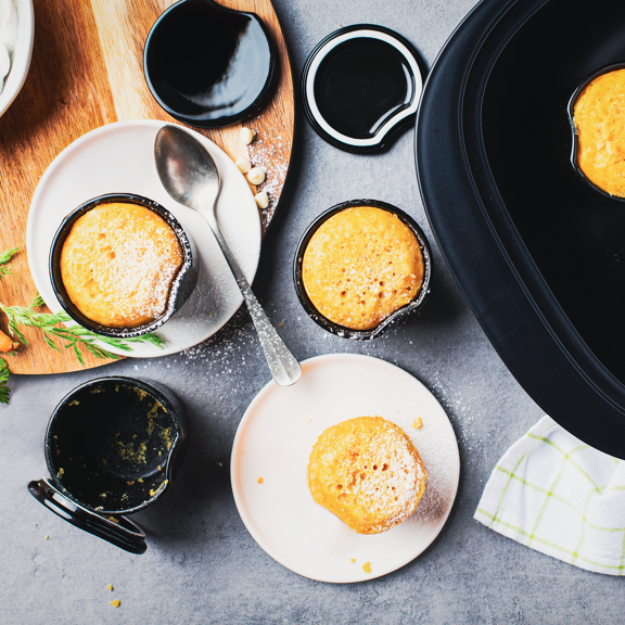 Muffin di carote in piccoli stampi alcuni nel Varoma di Bimby TM6 con ingredienti e utensili da cucina attorno