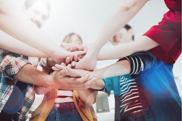Co-working startup business team and teamwork concept. Young team putting hands up in creative office. Happy and cheerful people giving strength motivation