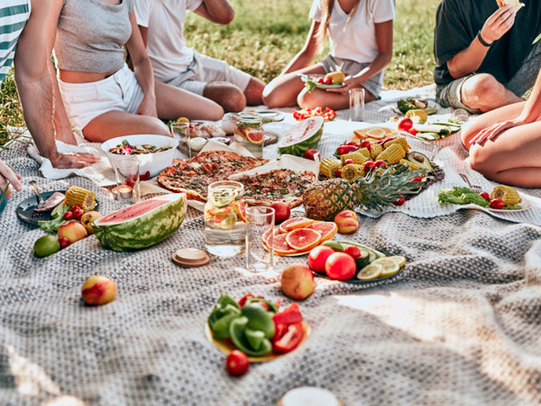 Group of friends having picnic on green meadow. Without a head.