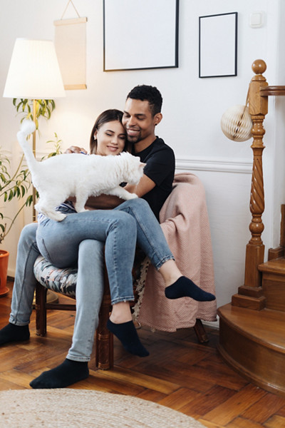 Jeune couple mixte, homme et femme, souriants et de bonne humeur, se reposant à la maison dans le salon avec un chat