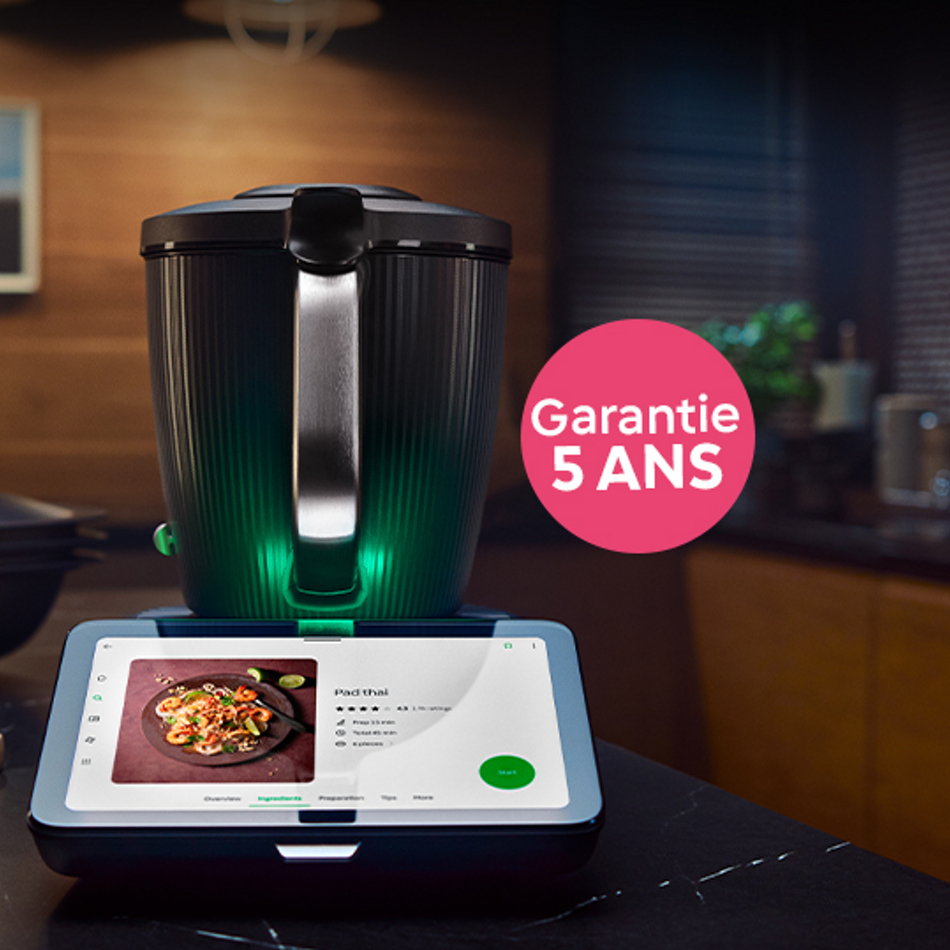 Thermomix® TM7 sur un plan de travail, recette affichée à l’écran et pastille « Garantie 5 ans ».