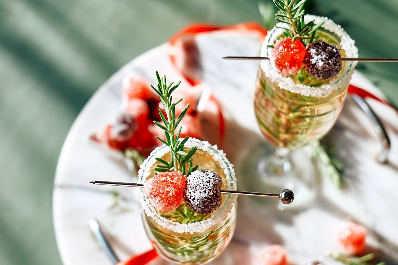 Christmas cocktail with sparkling wine, rosemary and cherry. Winter xmas and new year holidays champagne drink, top view.