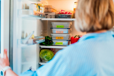 Femme qui range ses lunch box dans son réfrigérateur 