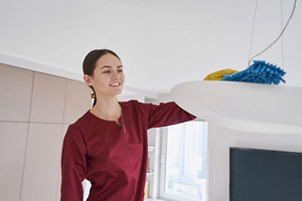 femme nettoyant les poussières sur un luminaire