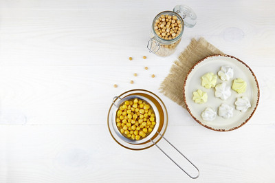 Meringue végétalienne à base d'aquafaba sur fond blanc en bois. Saumure de pois chiches, pois chiches bouillis. Remplace l'oeuf pour une recette végétalienne. Vue du haut.