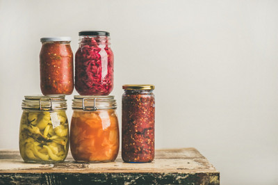 Les légumes colorés marinés ou fermentés de la saison d'automne dans des bocaux en verre placés en pile au-dessus d'un tiroir de cuisine vintage, fond de mur blanc, espace de copie. Conservation ou mise en conserve d'aliments à la maison en automne