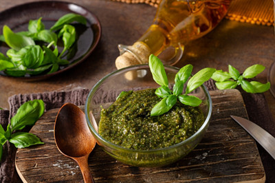 pesto dans un petit pot et feuilles de basilic 
