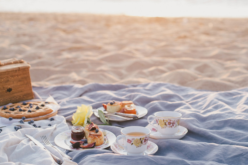 Beautiful picnic with pancakes, jam, american pie and tea on sunset at beach. 