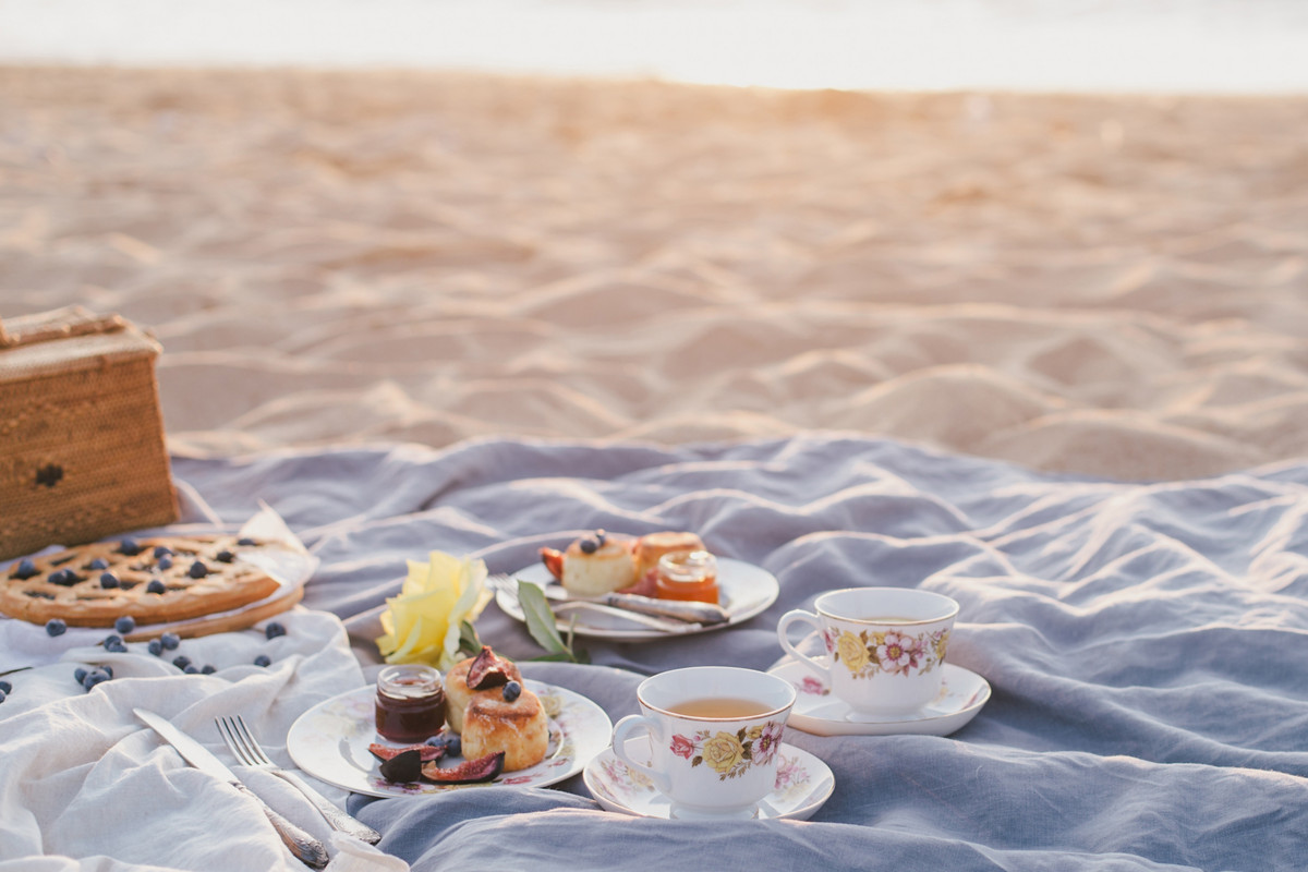 Beautiful picnic with pancakes, jam, american pie and tea on sunset at beach. 