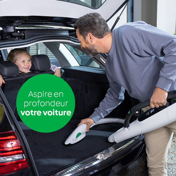 Un homme nettoie le coffre d une voiture avec la Brosseur Textile Kobold PB7 une enfant sourit sur la banquette arrière cercle vert avec texte