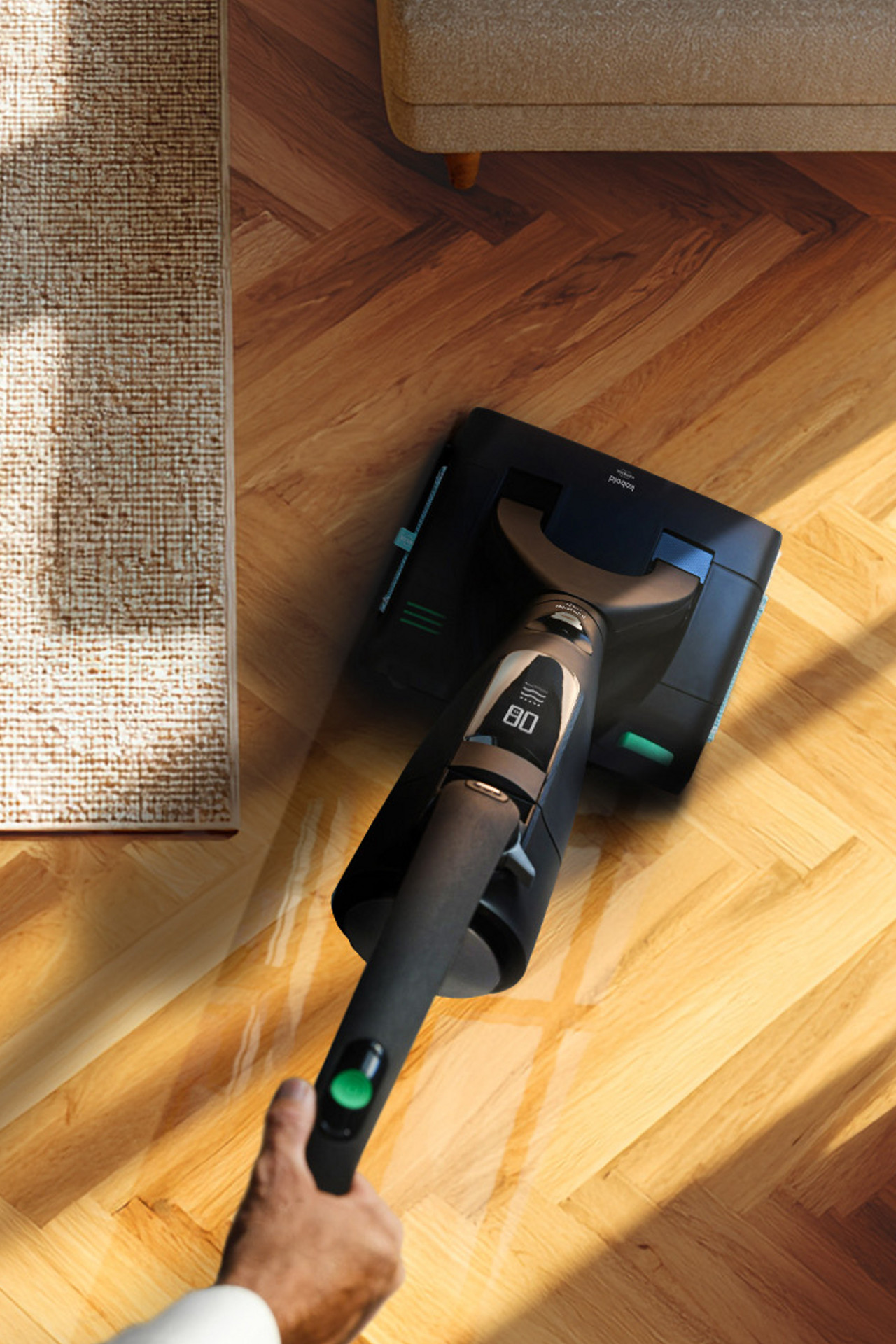 Personne passant l'aspirateur sur un parquet près d’un tapis avec l’aspirateur sans fil Kobold VK7 Special Edition Black.