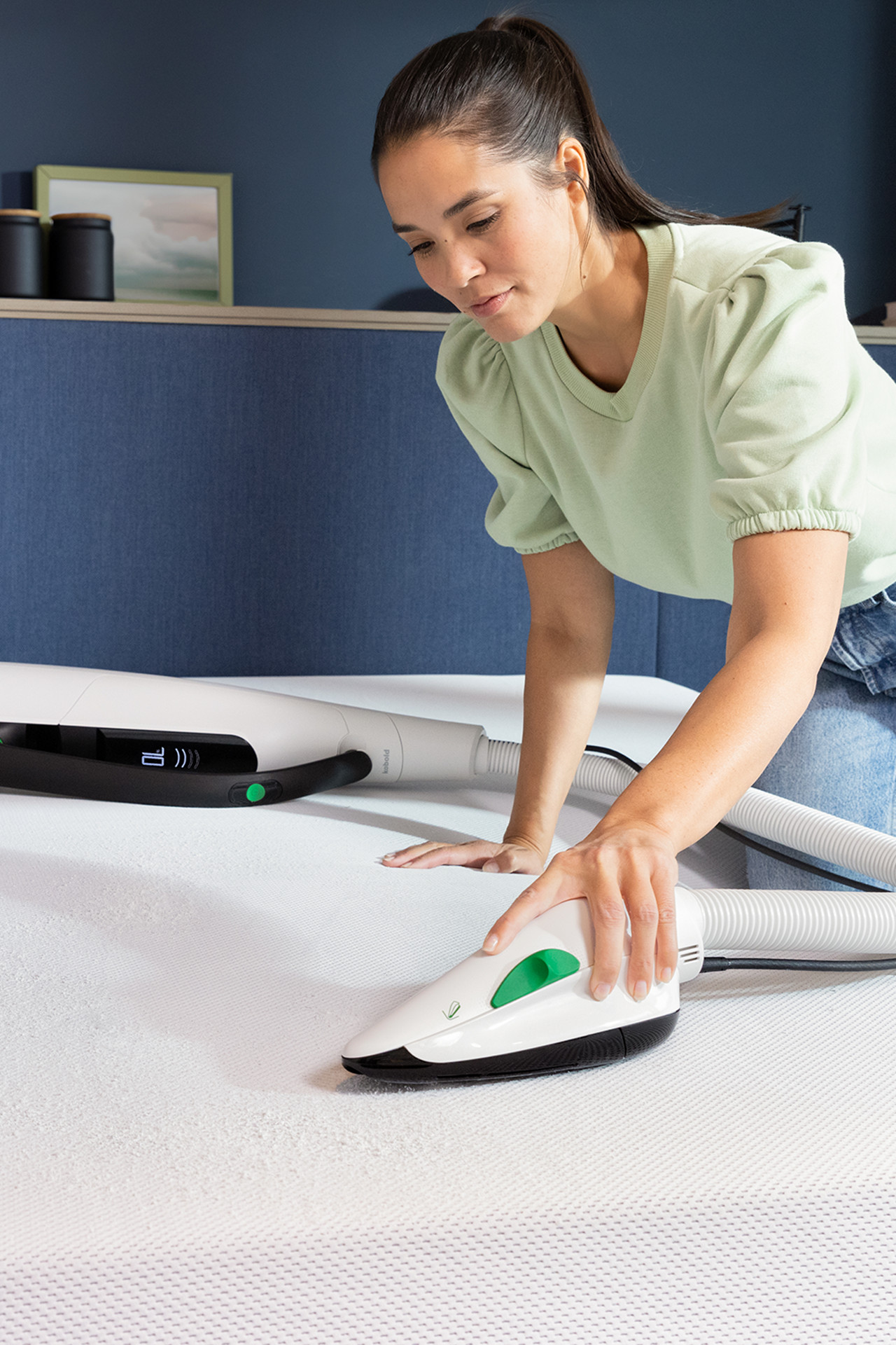 Personne nettoie un matelas avec la Brosseur Textile Kobold PB7, aspirateur sans fil Kobold VK7 en arrière-plan.