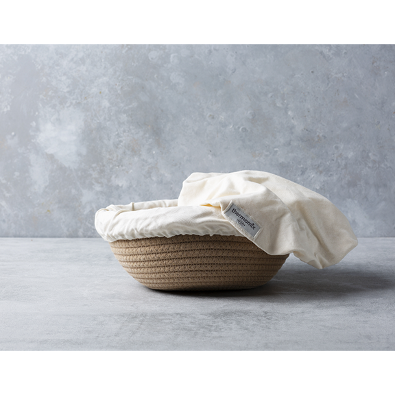 Panier rond tressé avec doublure crème portant l étiquette Thermomix sur surface grise