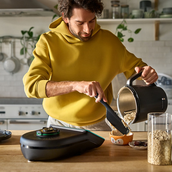 Un père verse sa recette de porridge au Thermomix dans un bol 