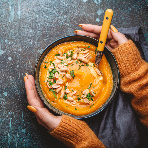 mains avec bol de soupe à la citrouille