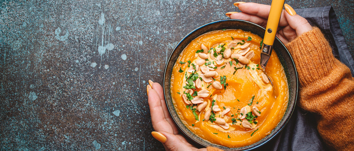 Femme qui tient un bol de soupe à la citrouille