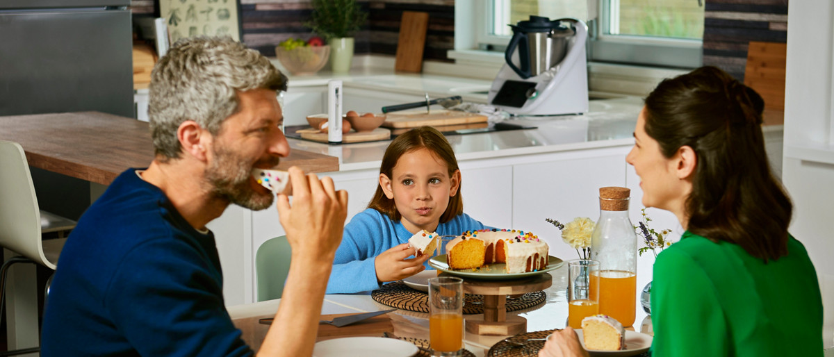 Un couple et leur fille déguste un gâteau réalisé à l'aide du robot pâtissier Thermomix