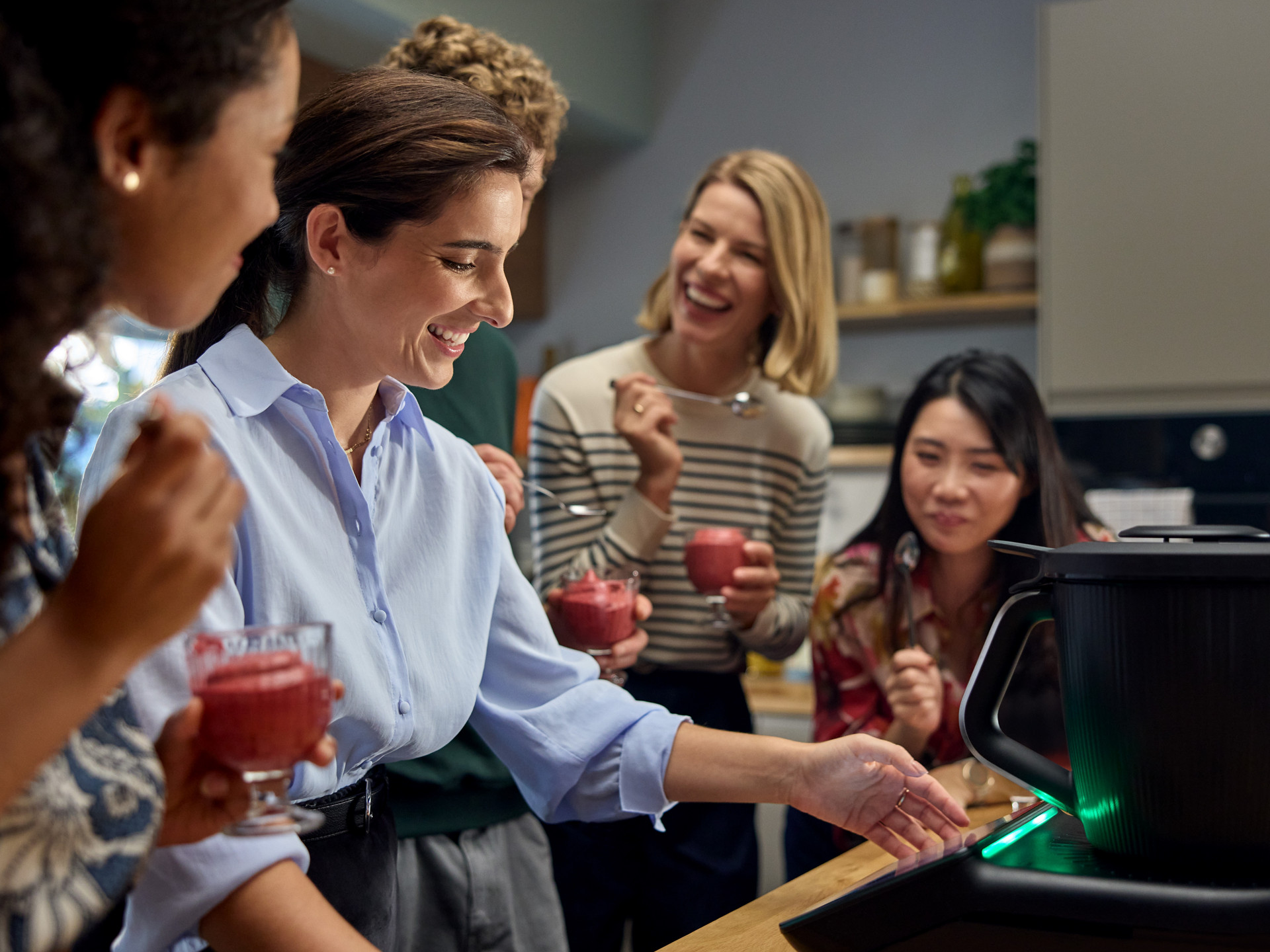 Groupe dégustant des boissons près d’un Thermomix® TM7 dans une cuisine moderne.