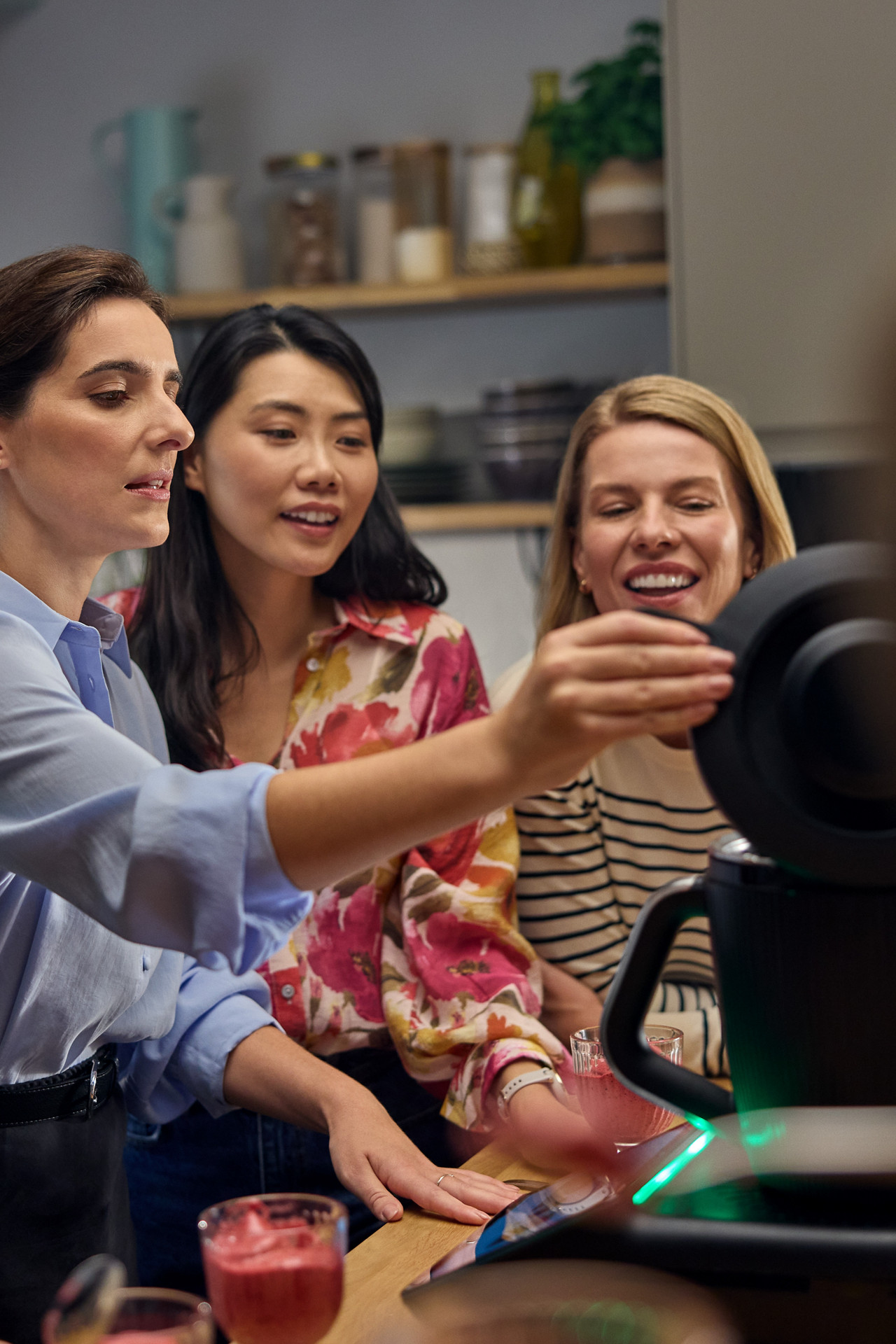 Des personnes réunies autour d’un Thermomix® TM7 dans une cuisine, préparant des smoothies ou des plats ensemble.