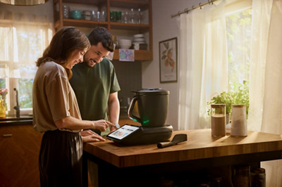 Un couple cherche une recette de gâteau sur la plateforme de recette Thermomix Cookidoo