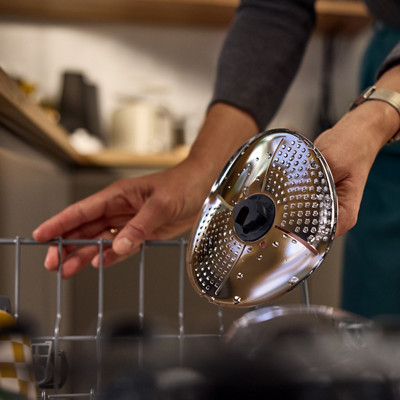 Une femme met le couvre lame Thermomix au lave-vaisselle