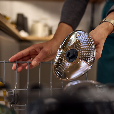 Une femme met le couvre lame Thermomix au lave-vaisselle