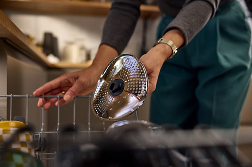 Une femme met son couvre-lame Thermomix au lave-vaisselle