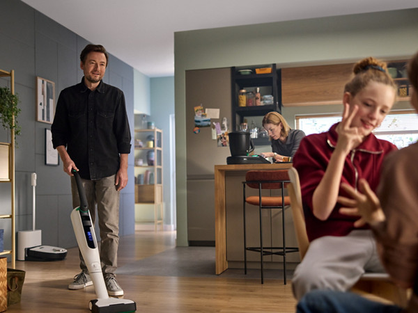 Un homme passe l'aspirateur-laveur sans fil Kobold VK7 dans sa salle à manger