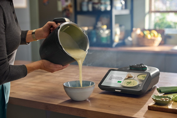 Une femme verse dans un bol de la soupe réalisé au Thermomix