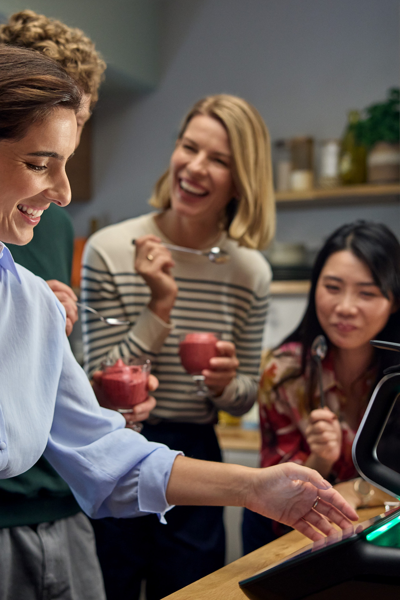 Plusieurs personnes dégustent un dessert autour d’un Thermomix® TM7 dans une cuisine.