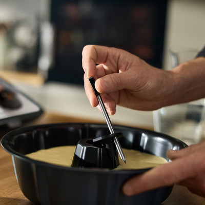 Une personne installe le Thermomix Sensor, la sonde de température Thermomix, dans un gâteau.