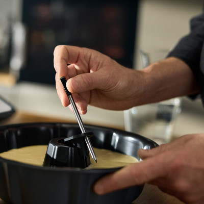 Une personne installe le Thermomix Sensor, la sonde de température Thermomix, dans un gâteau.