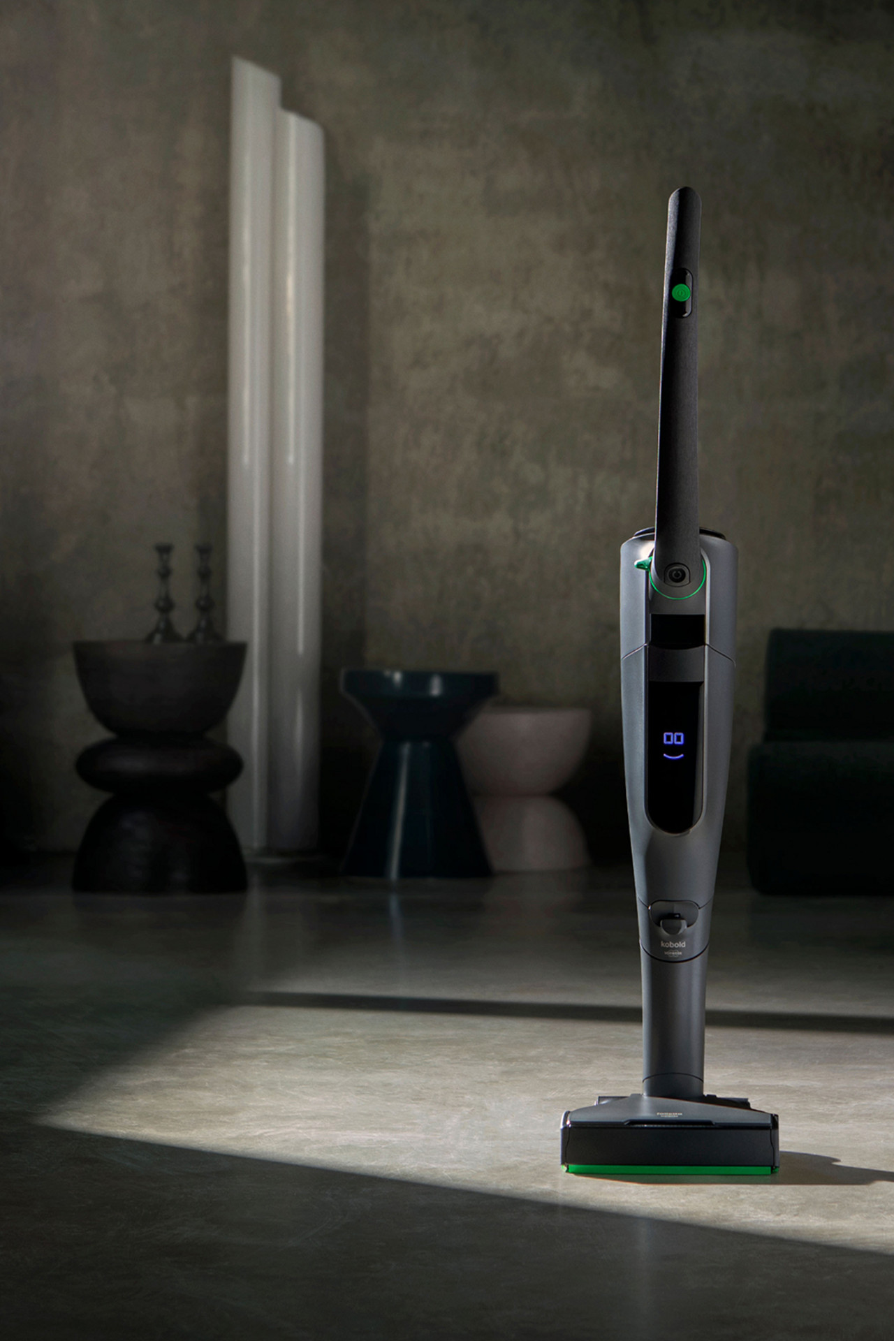 Kobold VK7 en posición vertical sobre el suelo de una sala de estar moderna con iluminación ambiental.