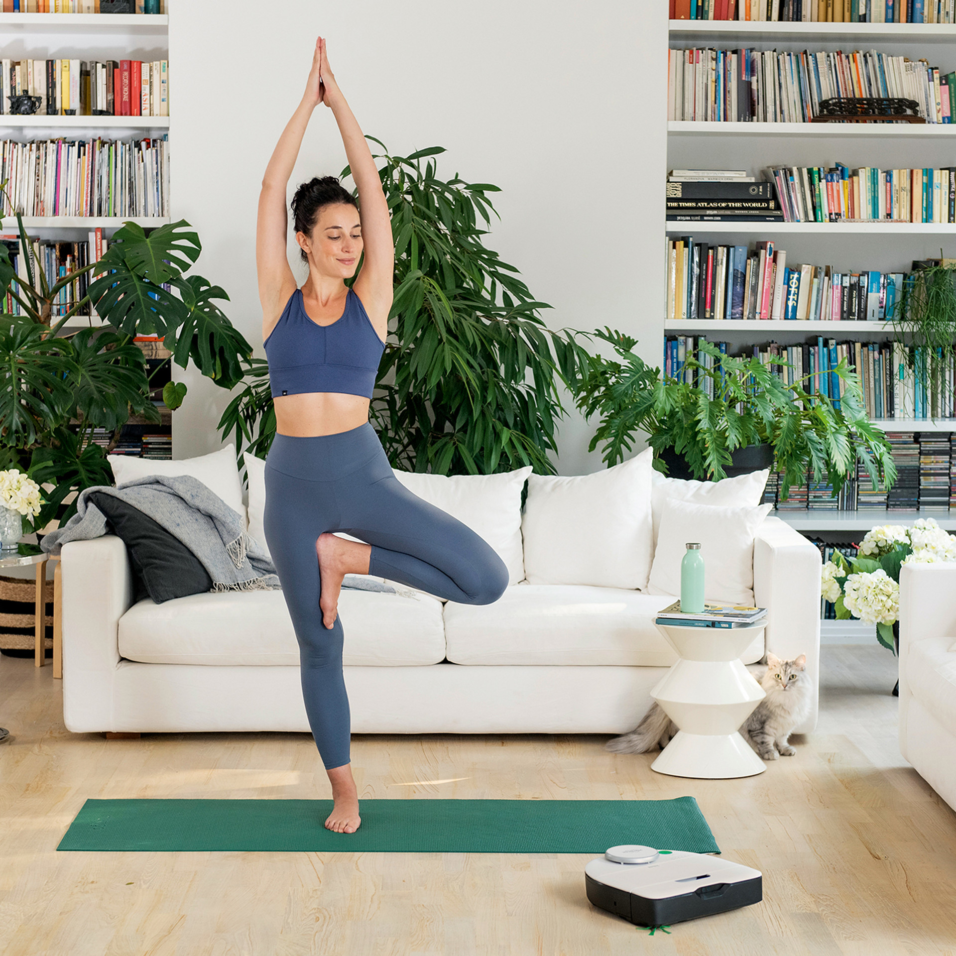 Frau macht Yoga im Wohnzimmer, neben einem Kobold VR7 Saugroboter.