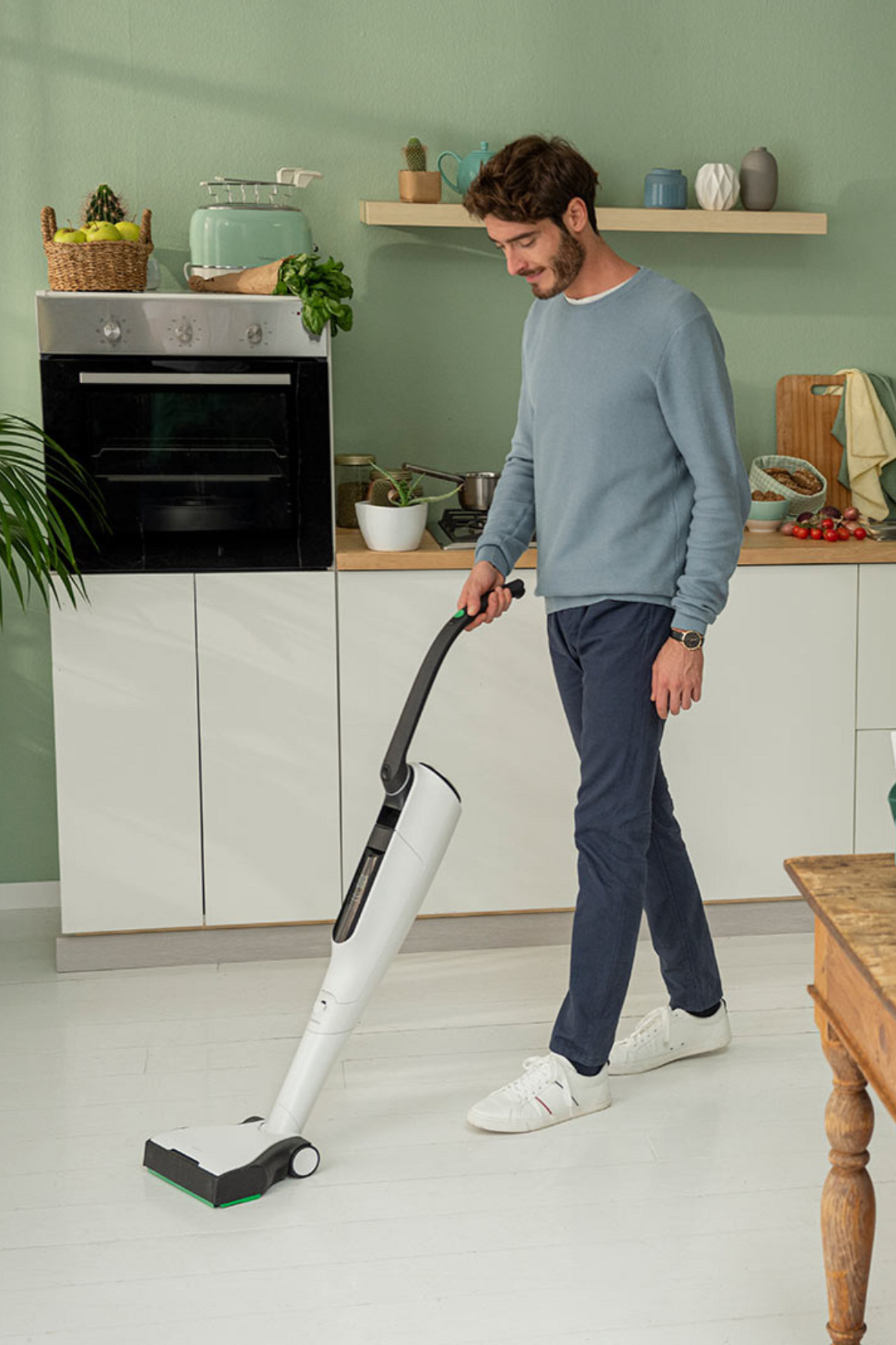 Uomo che pulisce il pavimento della cucina con Folletto VK7s.