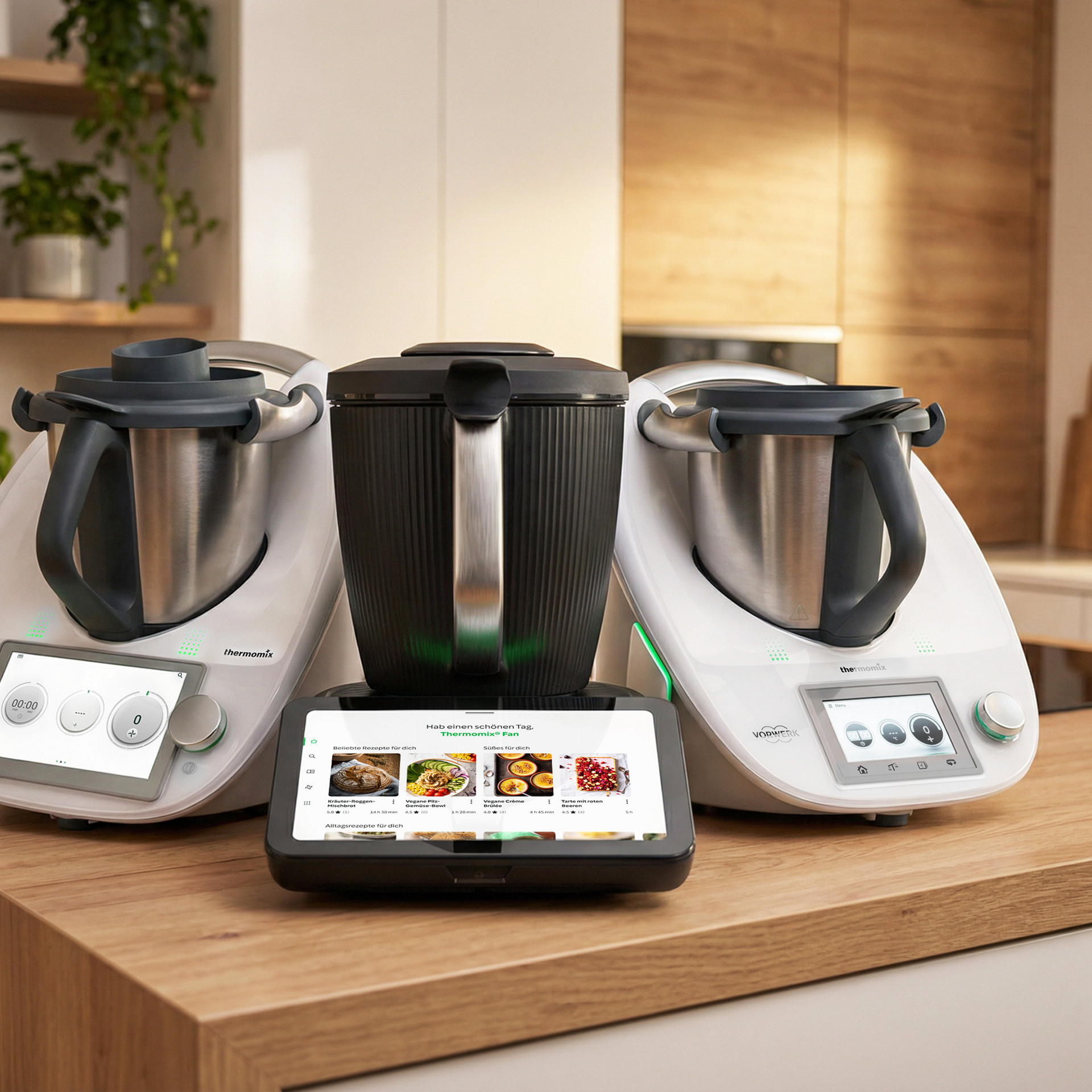 Thermomix® TM6 und Thermomix® TM7 auf einer Küchenarbeitsplatte mit digitalen Displays in einer modernen Küche.