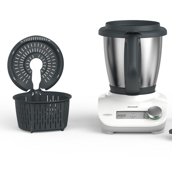 Thermomix Friend with mixing bowl simmering basket lid measuring cup and spatula arranged on a white surface
