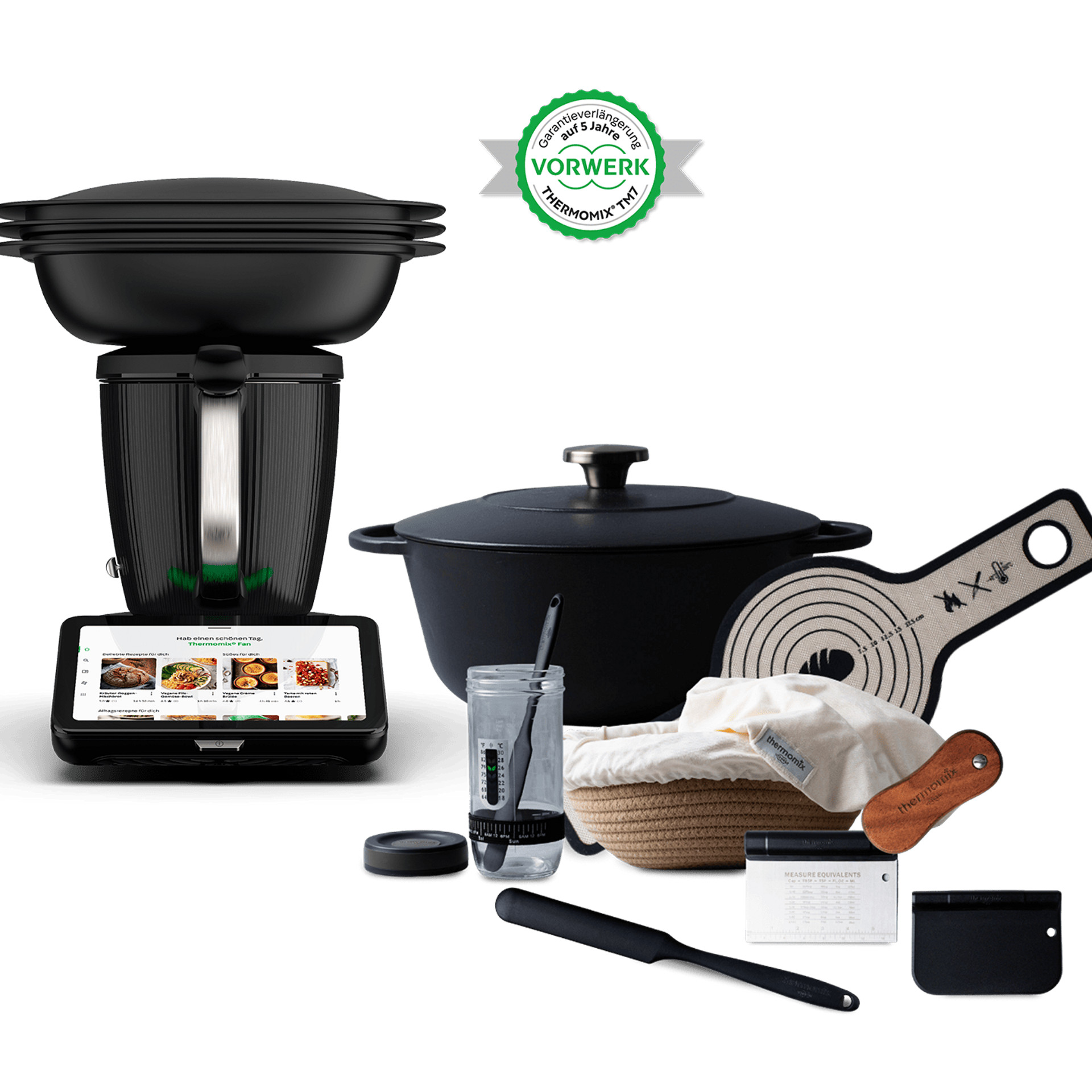 Thermomix® TM7 mit Varoma und Backzubehör, dazu Vorwerk Thermomix® Garantie-Emblem.