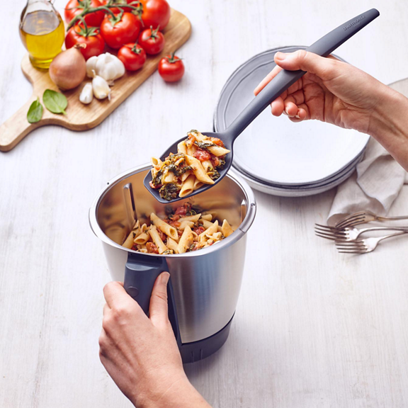 Hand serviert Pasta aus dem Thermomix TM6 Mixtopf frische Zutaten und Teller im Hintergrund