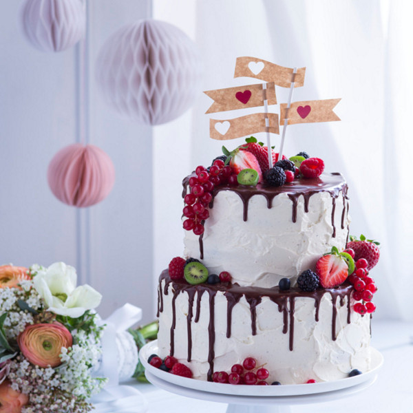 Verziere die Torte mit Beeren und Fähnchen