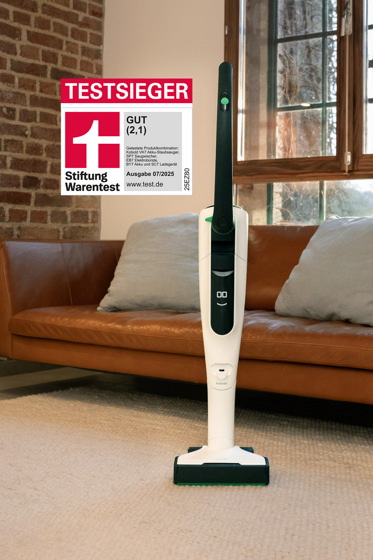 Kobold-Akkustaubsauger steht auf einem hellen Teppich; links im Bild das Stiftung-Warentest-Siegel „Testsieger – Gut (2,1)