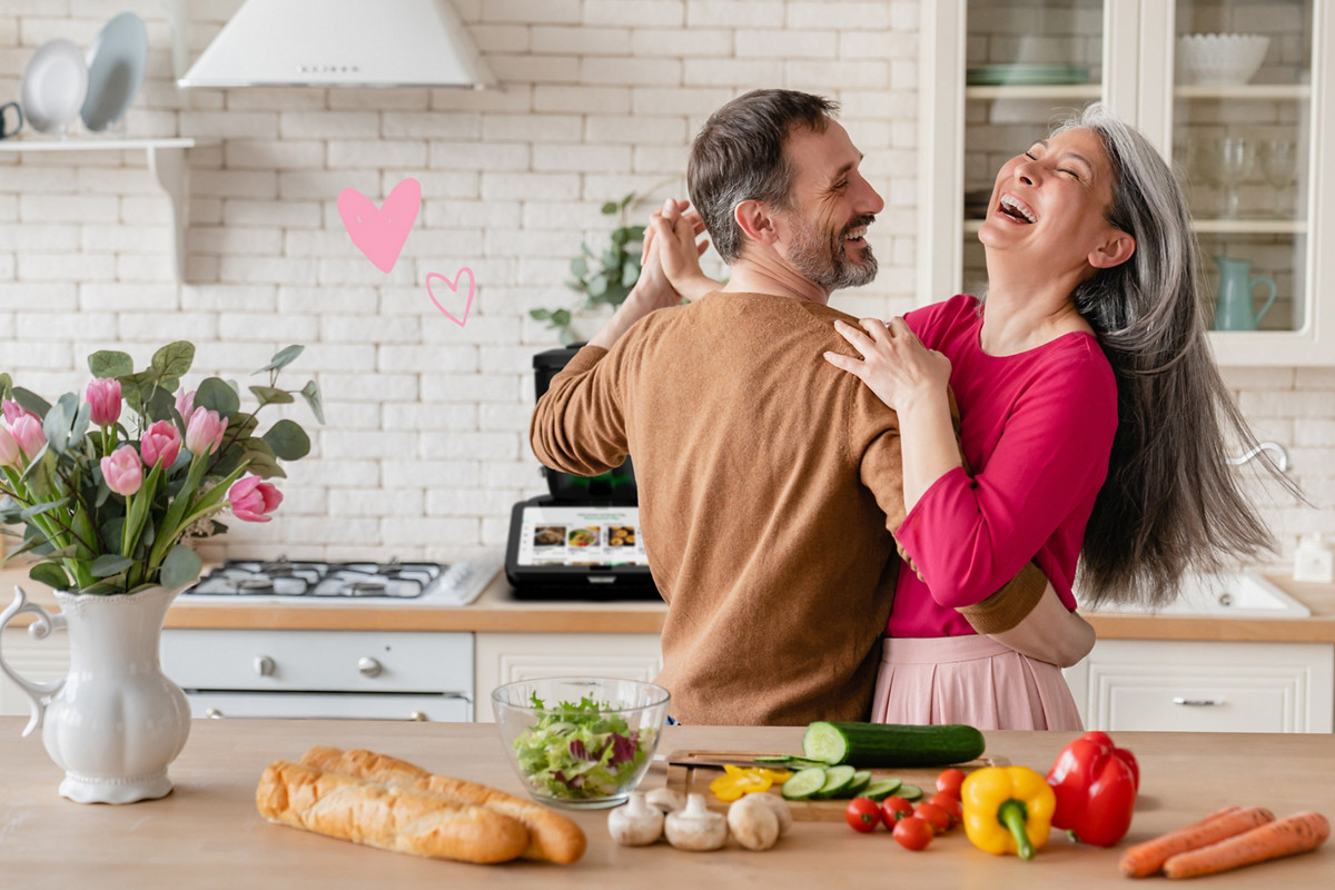 Paar tanzt in der Küche mit Thermomix im Hintergrund