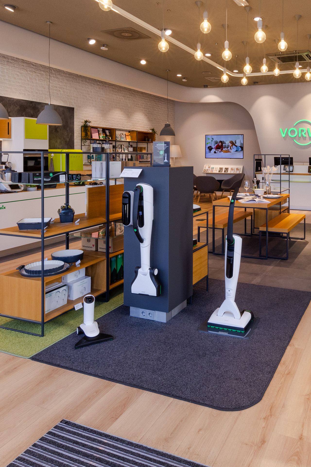 Vorwerk shop interior with Thermomix® TM6, Kobold VK7, Kobold VT300, and various accessories on display.
