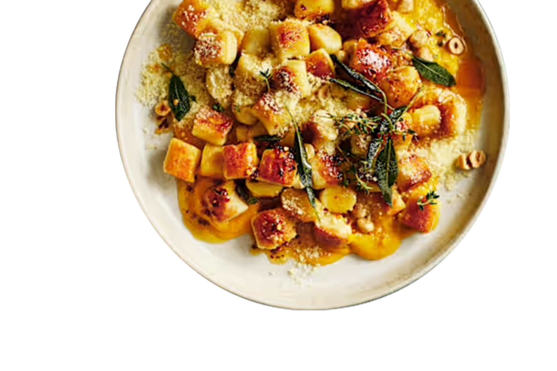 Plato de ñoquis dorados decorados con queso rallado, hierbas frescas y salsa de mantequilla.