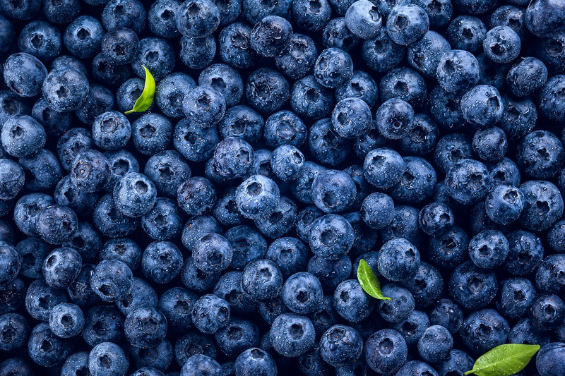 Fresh blueberry with drops of water on blue wooden background. Top view. Concept of healthy and dieting eating