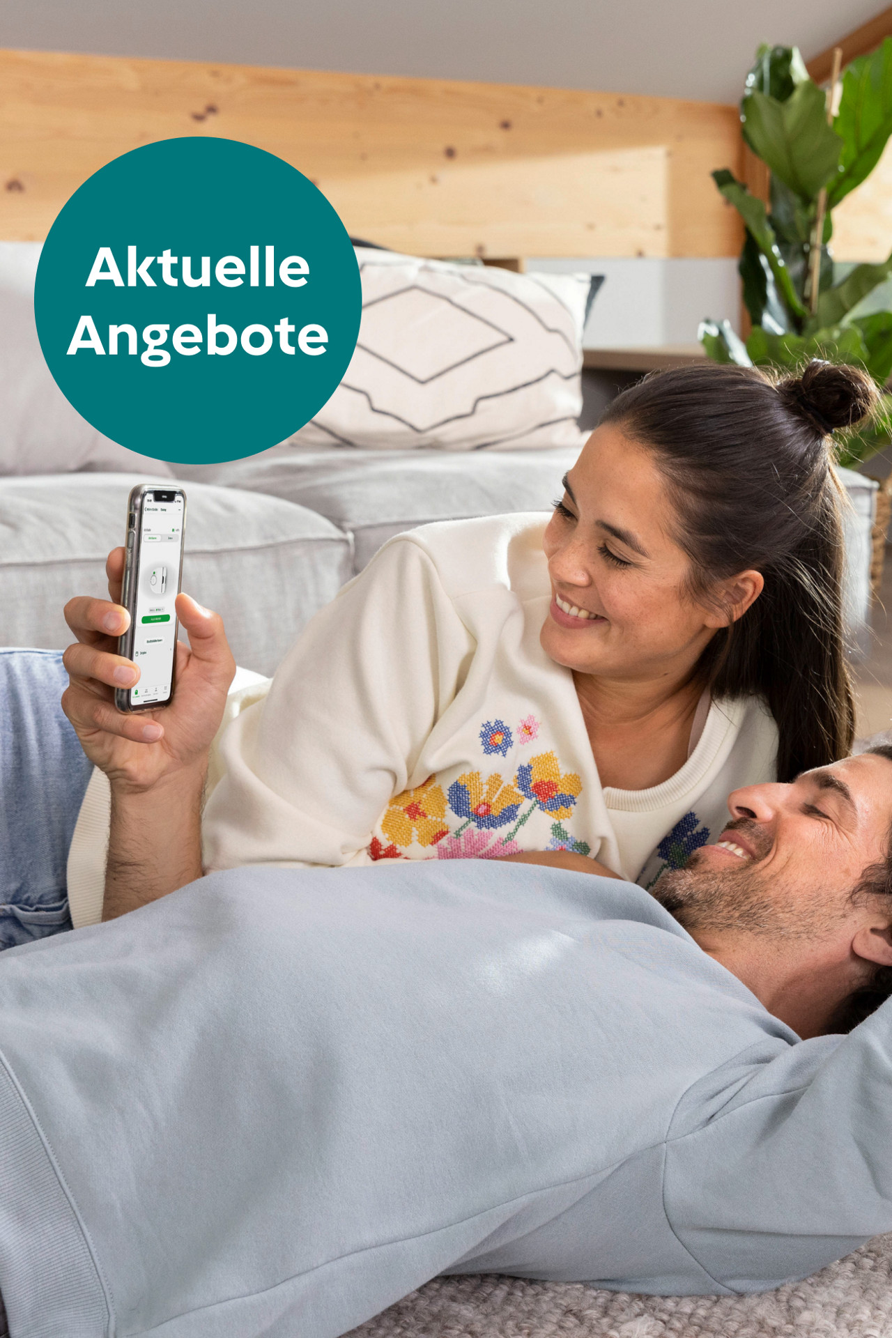 Zwei Personen entspannen, eine hält ein Smartphone mit Kobold VR7 Anzeige. Textblase zeigt „Aktuelle Angebote“.