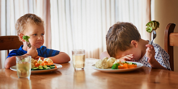 Shot of two unhappy little boys refusing to eat their vegetables at the dinner table