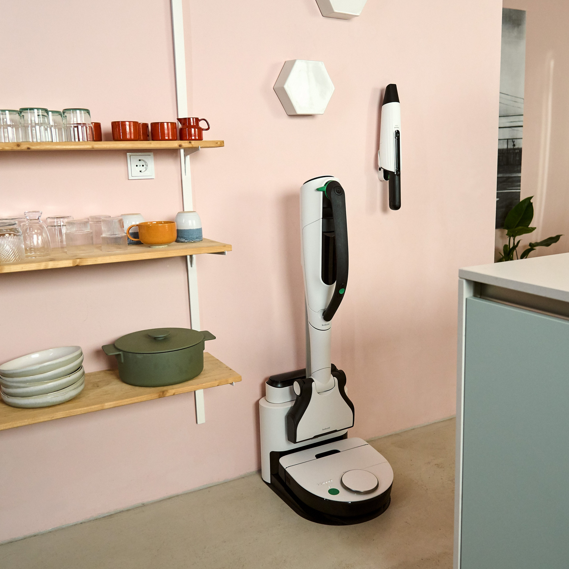 Aspirateur sans fil Kobold VK7 et robot aspirateur VR7 dans une cuisine, VK7 sur station de charge, VR7 en dessous.